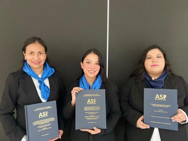Tres sustentantes con sus tesinas encuadernadas
